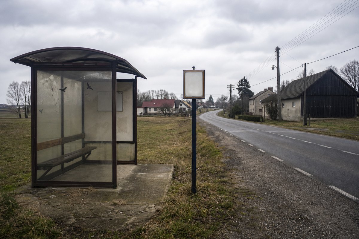 Pusty przystanek autobusowy przy drodze na obszarze wiejskim w pochmurny dzień.